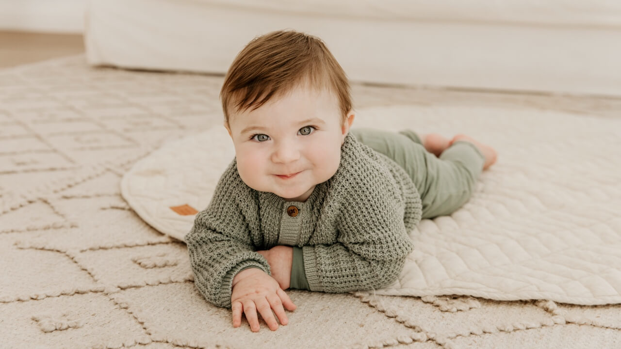 Baby lying on a cream linen play mat